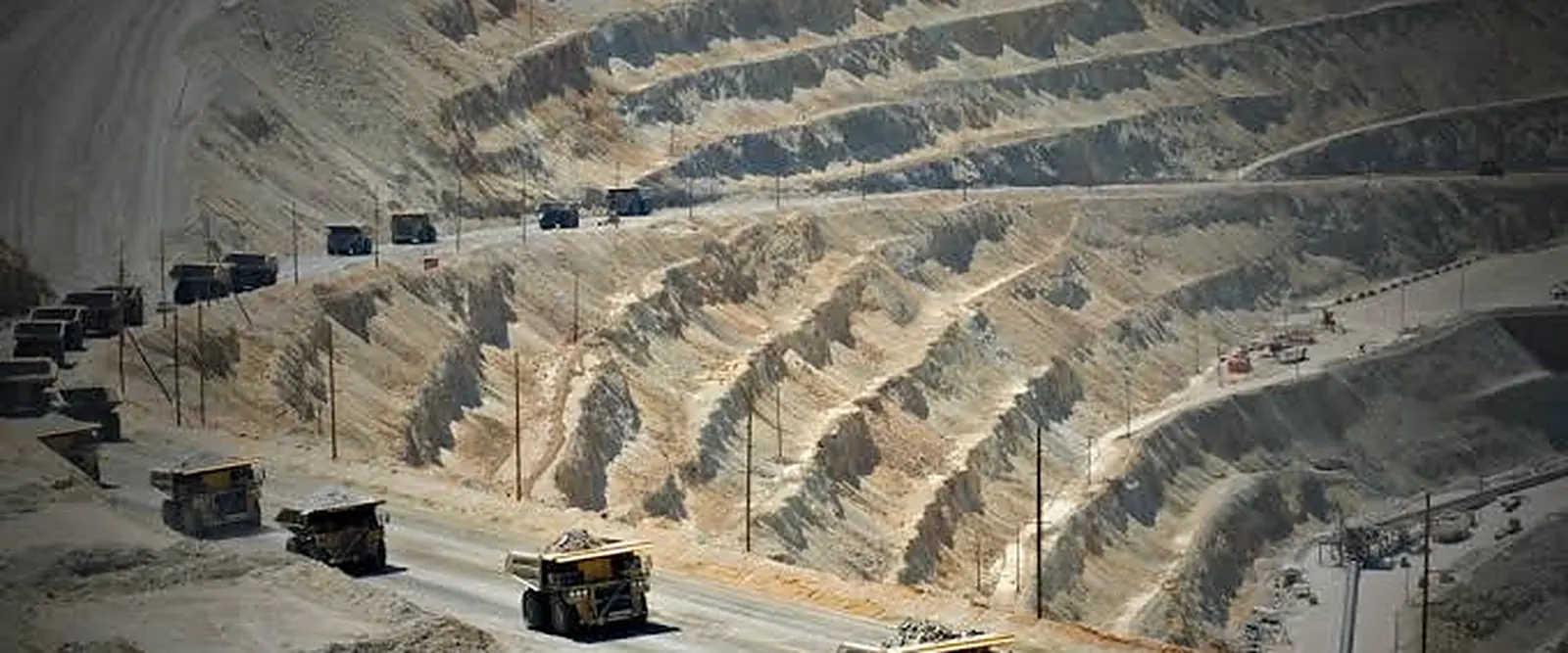 Haul trucks working a haul road in a terraced open-pit mine
